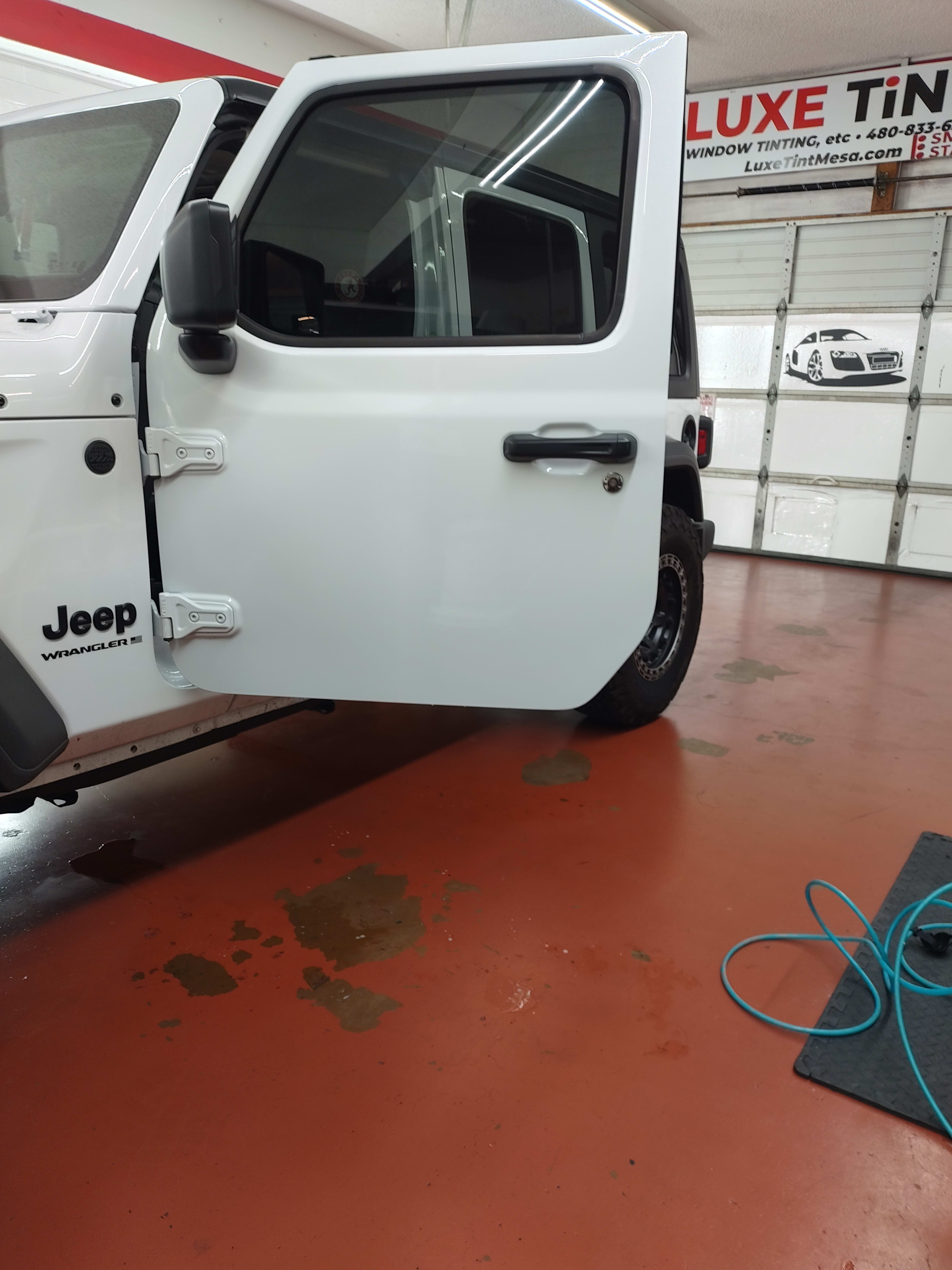 White Jeep Wrangler, door open, shop sign