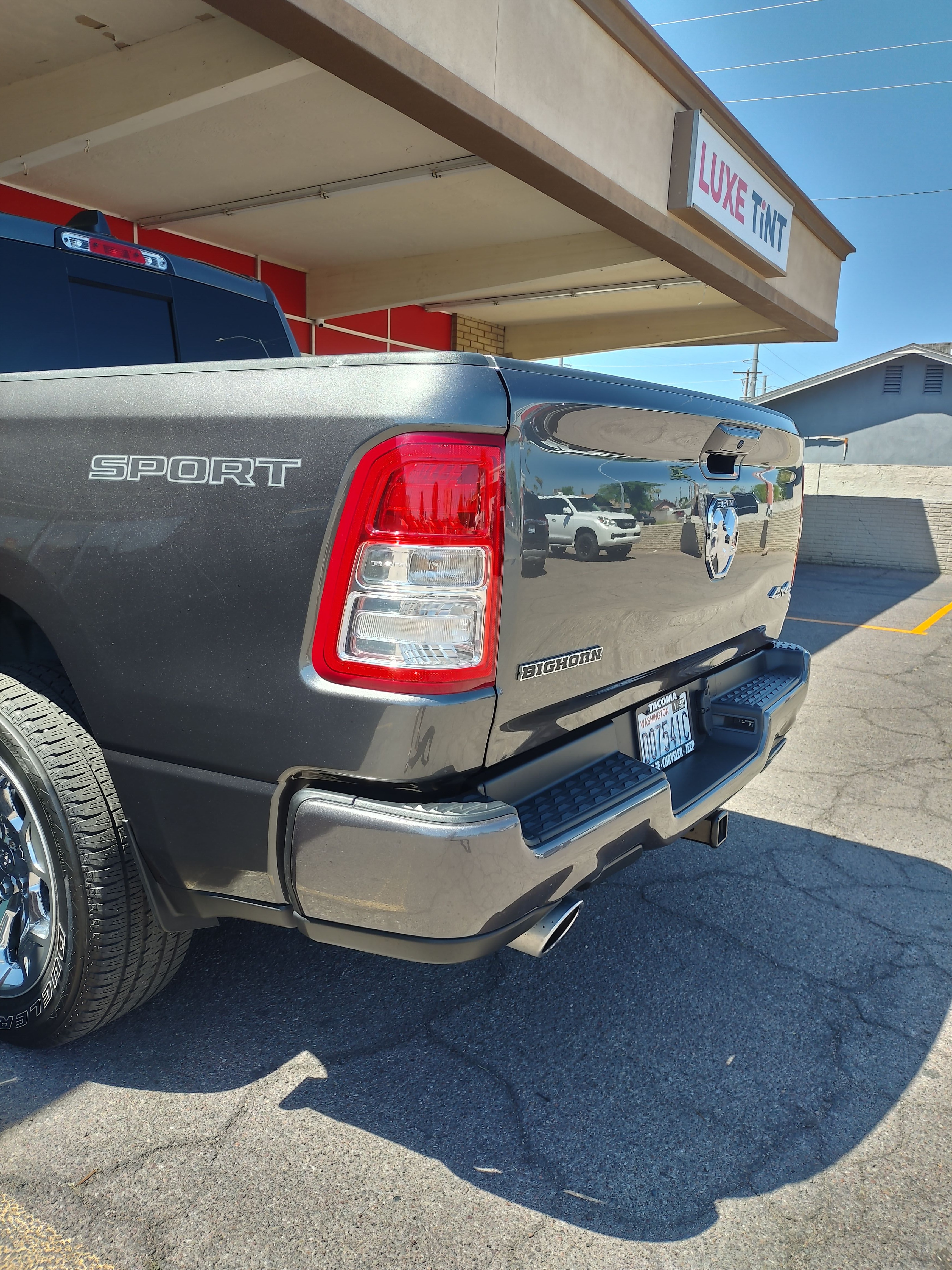 Grey Ram 1500 Sport outside the shop, rear